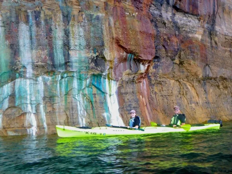 Kayakers paddle along the colorful cliffs of the Pictured Rocks
