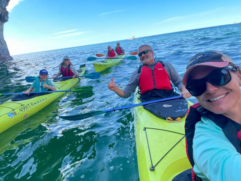 A family is all smiles taking a selfie on a Pictured Rocks Kayaking tour