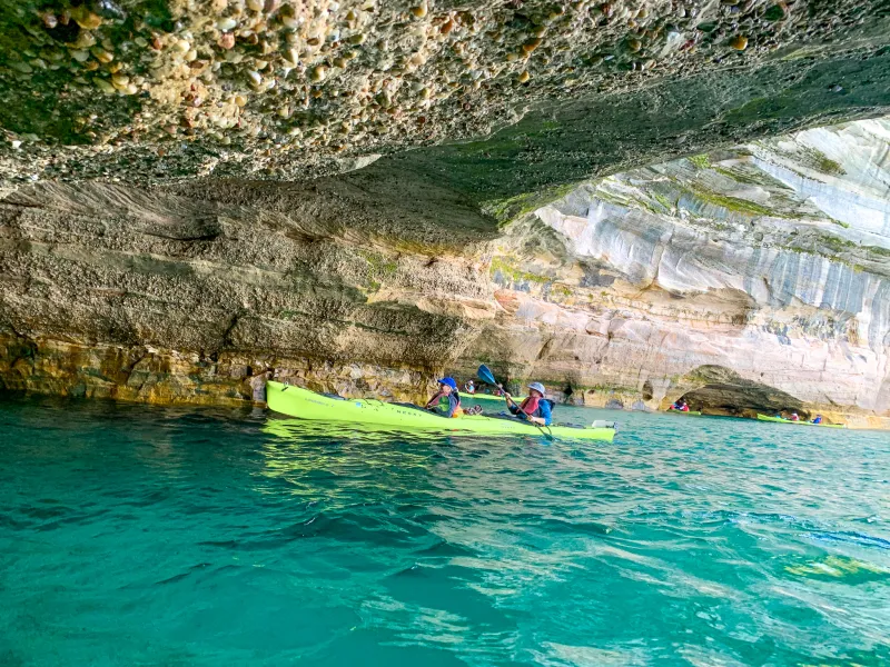 Paddling through a Pictured Rocks cave with barnacles visible on the ceiling.