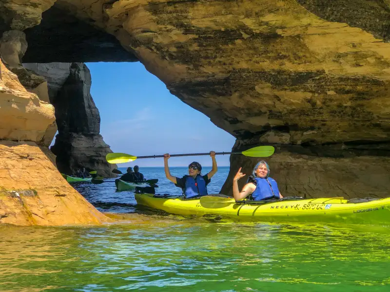 Two Younger Women Paddling Through a Sea Cave in Pictured Rocks National Lakeshore