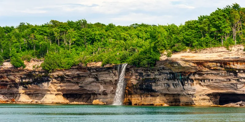 View of Spray Falls flowing into Lake Superior from a Pictured Rocks Cruise